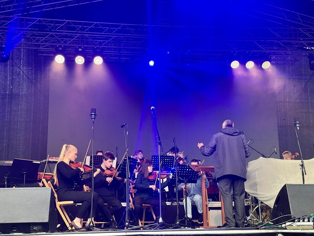 Ein Orchester auf einer blau beleuchteten Bühne